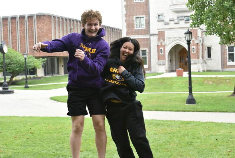 A female and male student jump into a shoulder bump in celebration during the Lawnsay Games